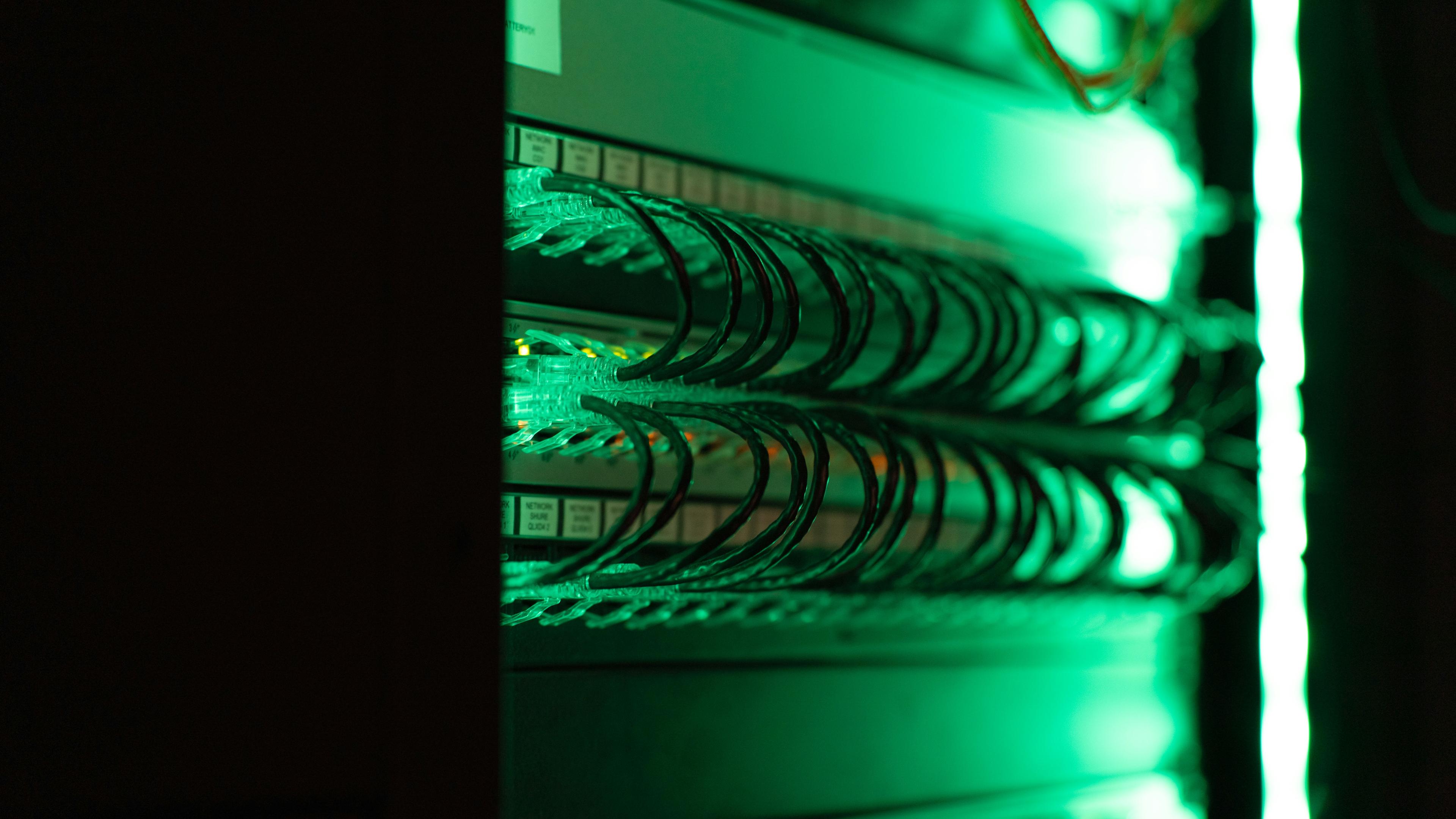 Network rack with green LED lights showing active connections and server infrastructure